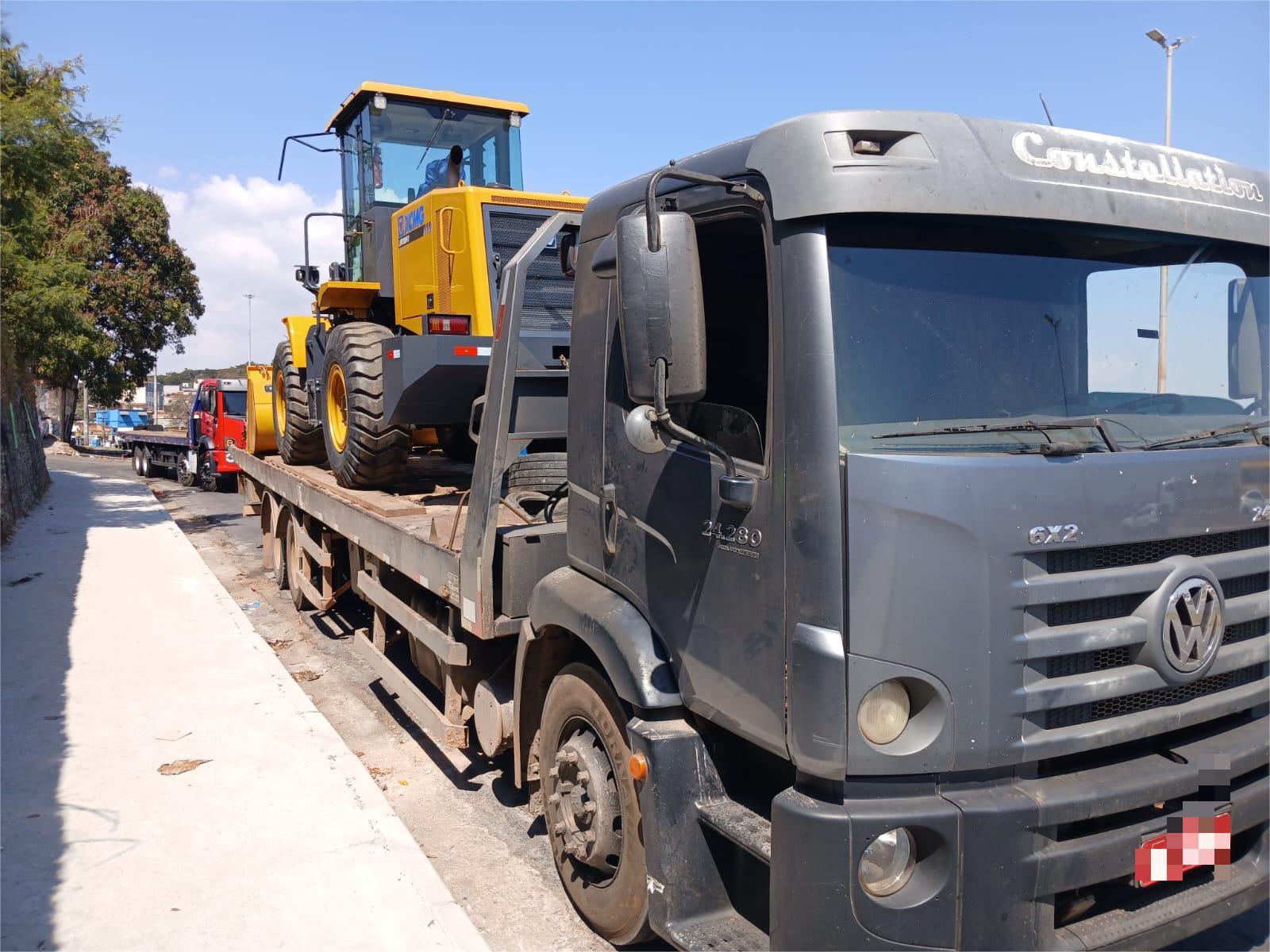 Caminhao prancha transportando equipamento de construcao